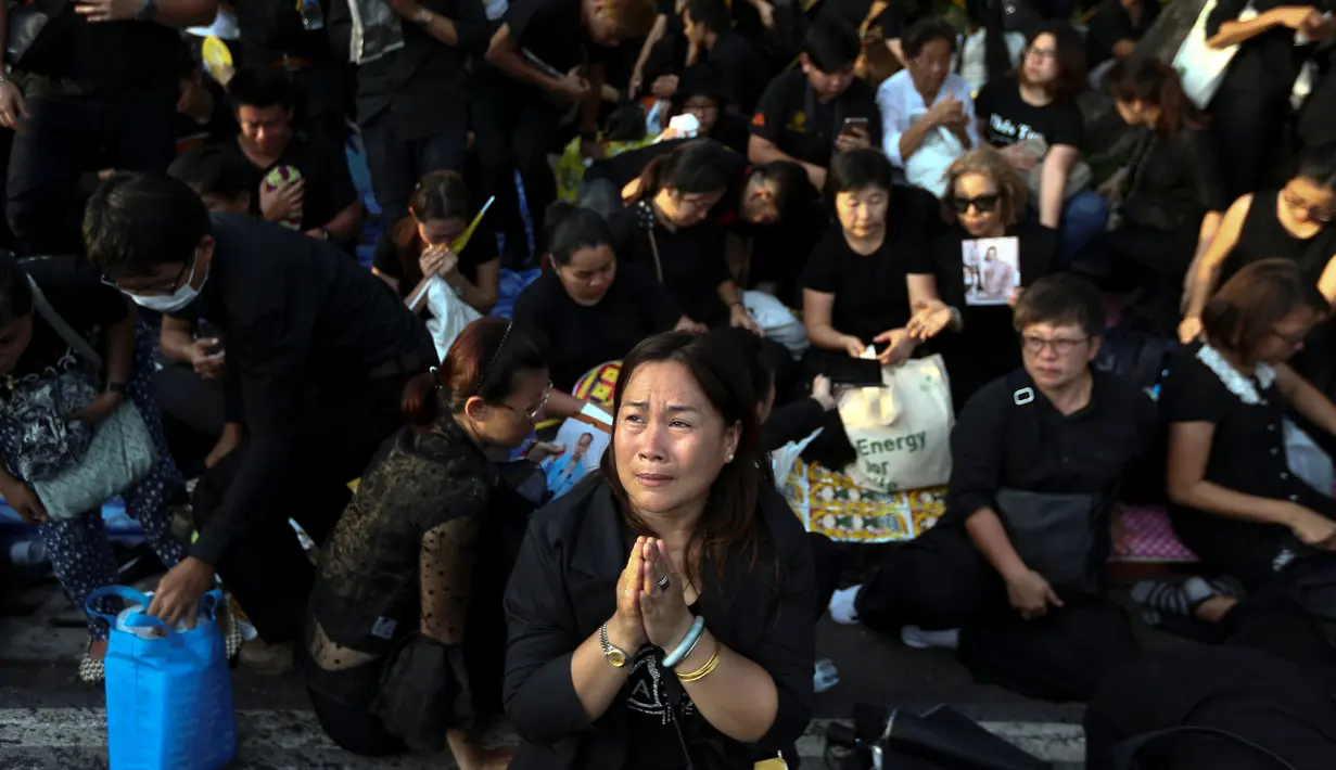Rakyat Thailand berdoa saat menunggu kedatangan mobil jenazah Raja Thailand Bhumibol Adulyadej di depan Grand Palace, Bangkok, Thailand, Jumat (14/10). (REUTERS / Athit Perawongmetha)