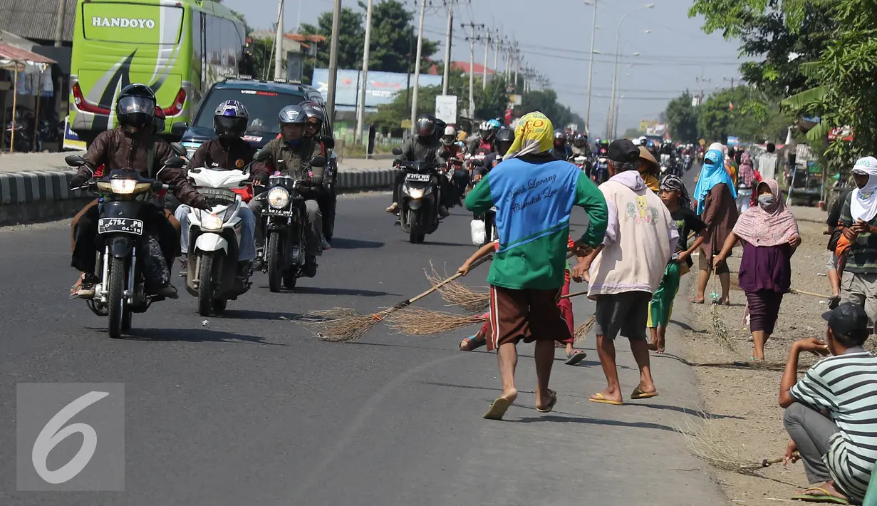 Sejumlah Penyapu jalan (Tawur) berjejer di pinggir jalan untuk mendapatkan uang receh di kawasan Indramayu, Subang, Jabar, Senin (11/7). Uang receh tersebut dilempar pengendara untuk para Tawur di jalur Pantura (Liputan6.com/Herman Zakharia)