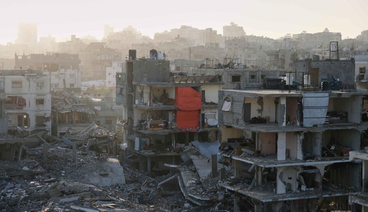 Masyarakat Jabalia berharap dapat kembali ke kehidupan normal, dengan akses yang lebih baik ke fasilitas dasar dan kesempatan untuk membangun kembali kehidupan mereka. Tampak dalam foto, kondisi salah satu blok apartemen yang rusak parah berdiri di Jabalia, di bagian utara Jalur Gaza, di mana para penghuni telah kembali tinggal di unit-unit yang hancur, menggantung tirai dan selimut untuk menutupi dinding yang hancur, Minggu 7 Desember 2025. (AP Photo/Jehad Alshrafi)