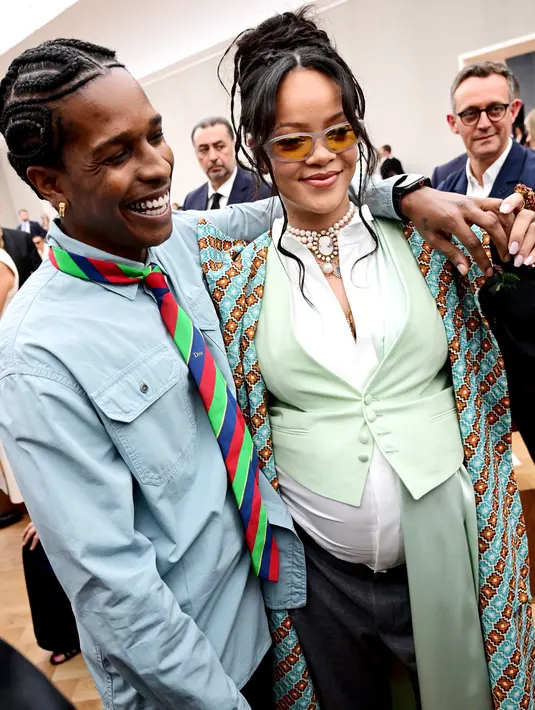 Ditemani ASAP Rocky, Rihanna terlihat energik dengan layered outfit. Bumil ini padukan kemeja putih dengan vest mint dan long outer bermotif [Dior]