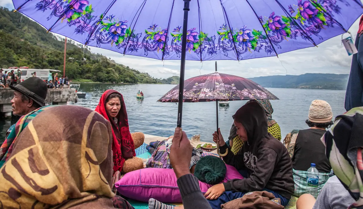 Anggota keluarga penumpang menunggu proses pencarian yang dilakukan tim SAR terhadap korban tenggelamnya KM Sinar Bangun di pelabuhan feri Danau Toba, Sumatera Utara, Rabu (20/6). Kapal tersebut membawa ratusan penumpang. (AFP PHOTO/IVAN DAMANIK)