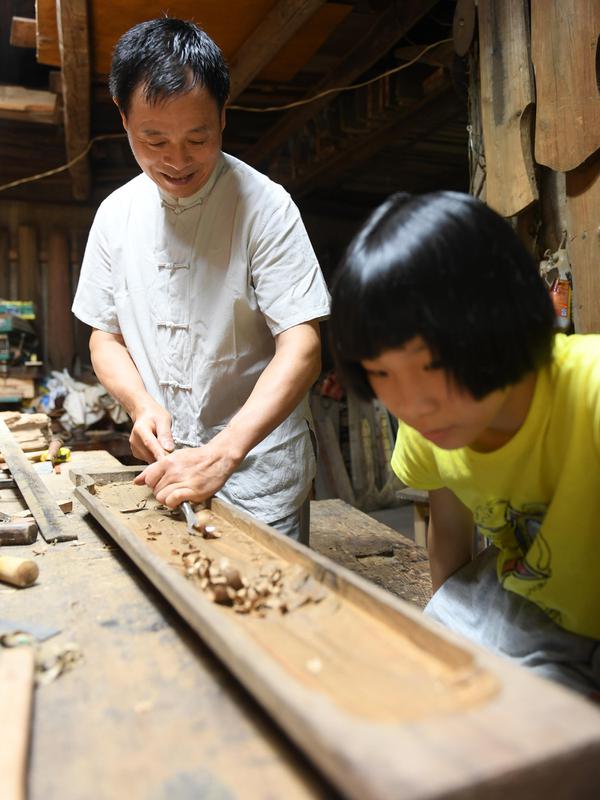 Ma Yuesi (kiri) membuat Guqin, alat musik tradisional China, di kediamannya di Desa Yalan, Distrik Yuhang, Hangzhou, Provinsi Zhejiang, China pada 30 Juni 2020. Selama bertahun-tahun, sebagai pewaris warisan budaya takbenda, Ma tak pernah berhenti meningkatkan keterampilannya. (Xinhua/Weng Xinyang)
