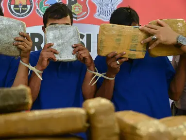 Para tersangka memperlihatkan paket ganja kering saat rilis kasus di Banda Aceh, Aceh, Kamis (23/5/2019). Satresnarkoba Polresta Banda Aceh mengamankan satu ton paket ganja, tiga tersangka dan satu unit truk tronton saat akan membawa narkotika ke Jakarta. (CHAIDEER MAHYUDDIN/AFP)