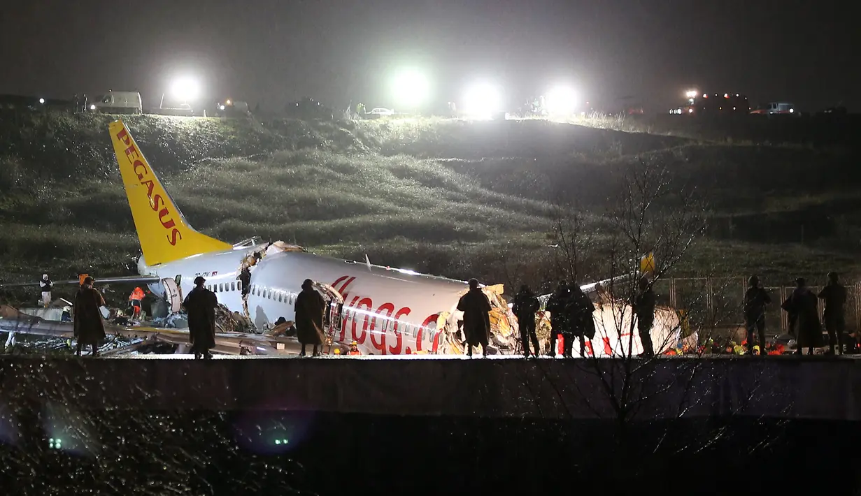 Tim penyelamat dan petugas pemadam kebakaran bekerja setelah sebuah pesawat tergelincir di landasan pacu Bandara Sabiha Gokcen, Istanbul, Turki, Rabu (5/2/2020). Pesawat milik maskapai Pegasus Airlines tersebut keluar dari landasan pacu dan terbelah menjadi tiga bagian. (AP Photo/Emrah Gurel)