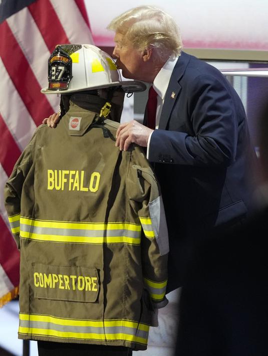 Kandidat presiden dari Partai Republik, mantan Presiden Donald Trump, mencium helm Corey Comperatore saat Konvensi Nasional Partai Republik di Fiserv Forum di Milwaukee, Wisconsin, Kamis (17/7/2024). (AP Photo/Charles Rex Arbogast)