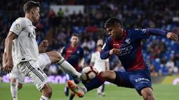 Gelandang Real Madrid, Marcos Llorente, berebut bola dengan striker Huesca, Cucho Hernandez, pada laga La Liga Spanyol di Stadion Santiago Bernabeu, Madrid, Minggu (31/3). Madrid menang 3-2 atas Huesca. (AFP/Javier Soriano)