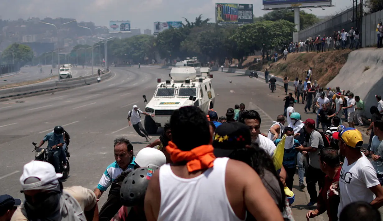 Pengunjuk rasa pendukung oposisi, Luis Alejandro berusaha menghindar dari kendaraan taktis Garda Nasional Venezuela di luar pangkalan militer 'La Carlota' di Caracas, Venezuela (30/4/2019). Luis ditabrak oleh tentara yang menghalau aksi demonstrasi tersebut. (Reuters/Ueslei Marcelino)