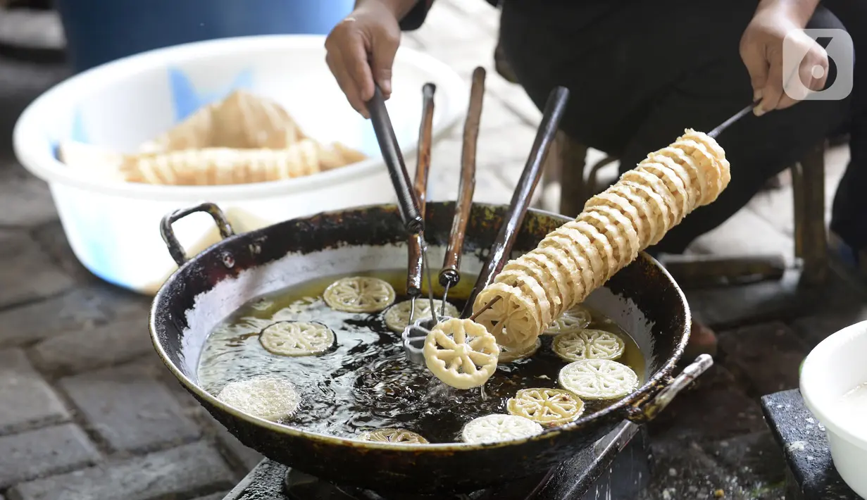 Pekerja menggoreng jajanan tradisional kembang goyang di Kelurahan Karangan, Setu, Tangerang Selatan, Banten, Kamis (6/8/2020). Jajanan kue kering berbentuk bunga tersebut dijual dengan harga Rp 5 ribu per bungkus. (merdeka.com/Dwi Narwoko)