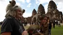 Sejumlah monyet memanjat di pundak wisatawan selama Festival Monkey Buffet, kuil Phra Prang Sam Yot, Bangkok, Thailand (27/11). Sejumlah wisatawan juga bisa memberikan buah-buahan dan sayur selama berlangsungnya festival. (REUTERS/Chaiwat Subprasom)