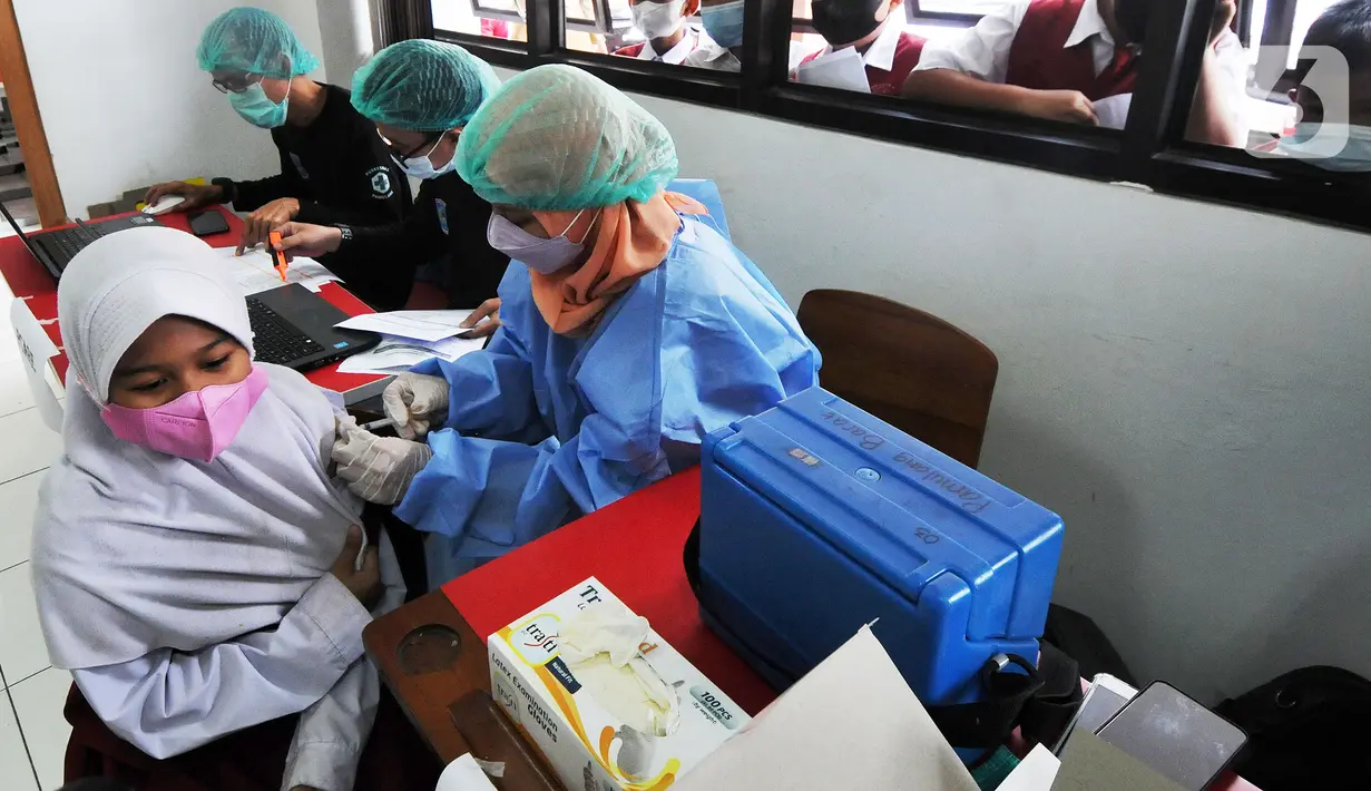 Petugas kesehatan menyuntikkan vaksin COVID-19 kepada siswa di SDN 02 Ciater, Tangerang Selatan, Selasa (14/12/2021). Mulai Hari ini, 11 provinsi di Indonesia secara serentak melaksanakan vaksinasi COVID-19 dengan sasaran anak berusia 6 hingga 11 tahun. (merdeka.com/Arie Basuki)