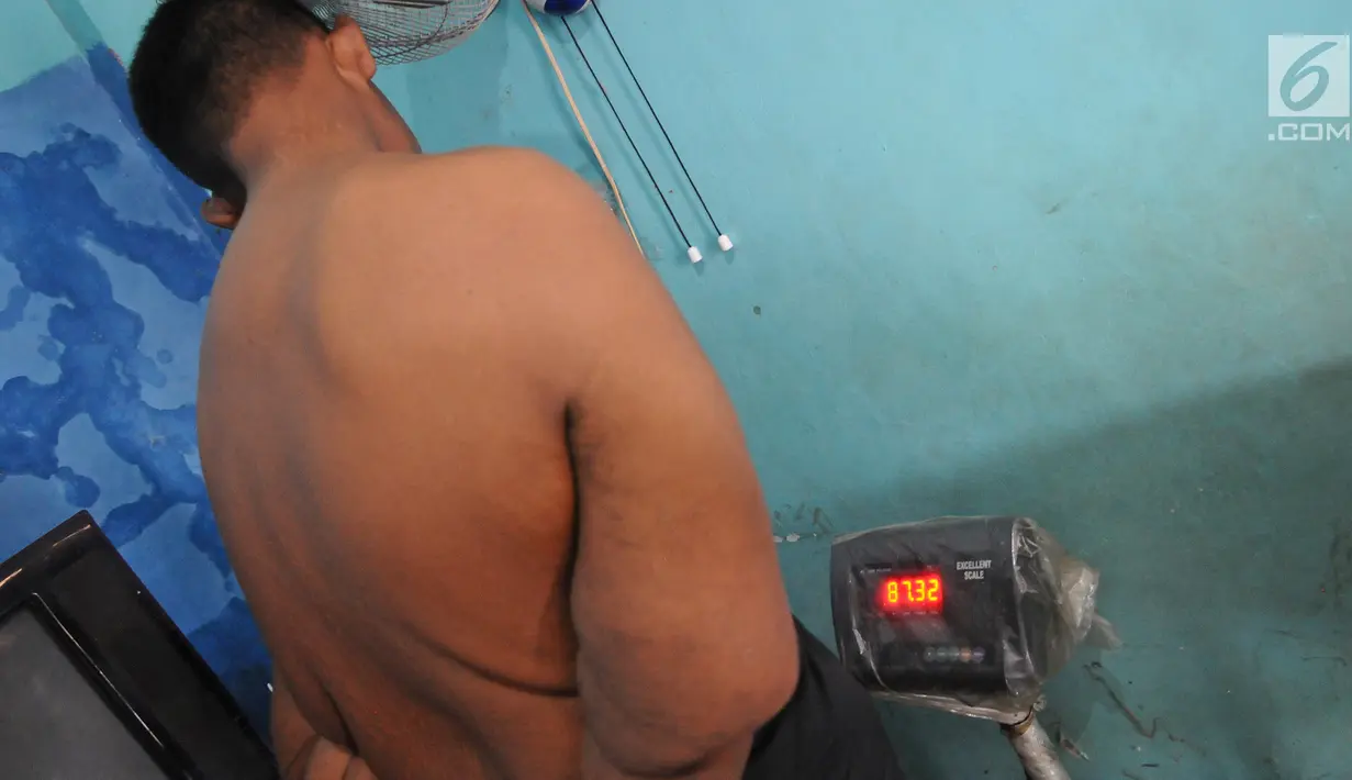 Arya Permana mengukur berat badan dikediamannya di kawasan Karawang, Jawa Barat, Selasa (9/4). Arya Permana diketahui memiliki berat badan hingga 192 kg, sekarang sudah turun 105 kg menjadi 87 kg pasca operasi lambung. (Liputan6.com/Herman Zakharia)