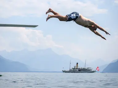 Seorang pria melompat ke Danau Jenewa di Saint Saphorin, Swiss barat saat gelombang panas melanda seluruh Eropa utara (31/7). Akibat gelombang panas suhu di beberapa bagian Swiss mencapai 35 Derajat. (AFP Photo/Fabrice Coffrini)