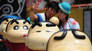 Pengunjung berfoto selfie saat pameran Crayon Shin-chan di Shenyang, China, 11 Juli 2015. Pameran ini menandai ulang tahun ke 25 dari seri manga Jepang, Crayon Shin-chan. (CHINA OUT AFP PHOTO)