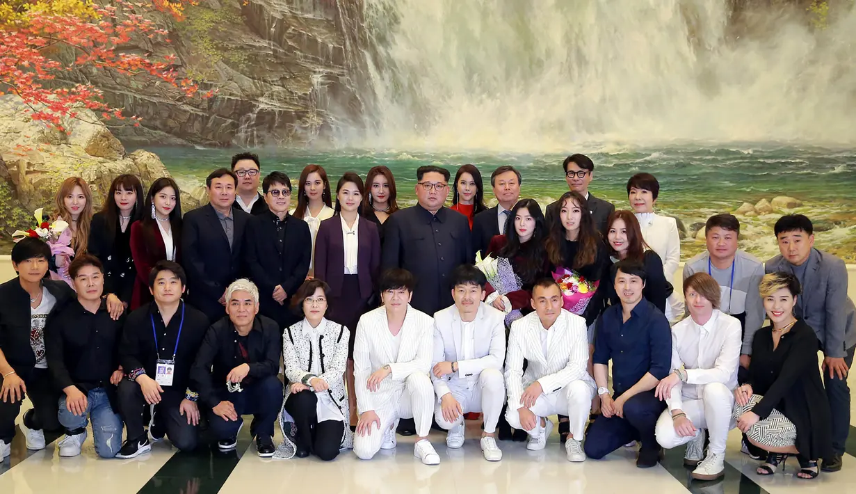 Pemimpin Korea Utara Kim Jong-Un (tengah) dan istrinya Ri Sol-Ju (tengah kiri) berfoto bersama sejumlah bintang K-pop dan musisi dari Korea Selatan di East Pyongyang Grand Theatre, Korea Utara (4/1). (AFP Photo/KCNA)