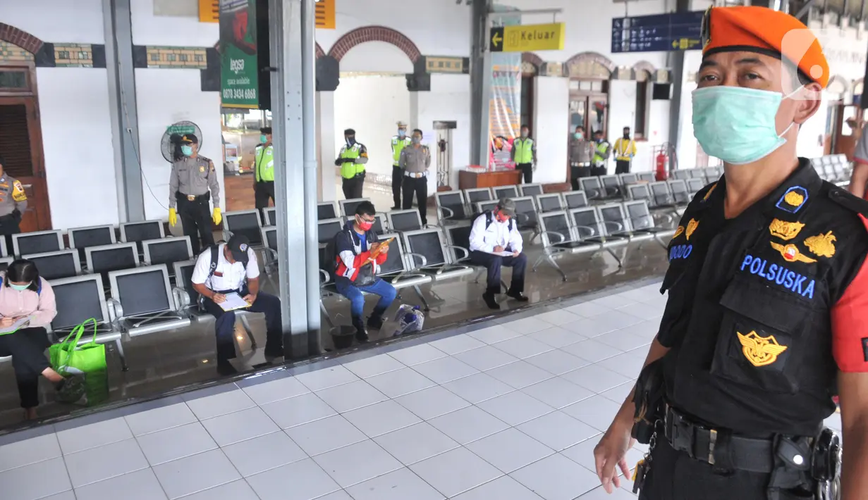 Petugas gabungan dari Polrestabes Semarang menyemprot larutan disinfektan kepada penumpang yang turun di Stasiun KA Tawang, Sabtu (28/3/2020). Selain sterilisasi, petugas juga melakukan pencatatan penumpang yang turun untuk data pengawasan guna menekan penularan Corona COVID-19. (Liputan6.com/Gholib