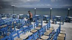 Seorang karyawan menyiapkan teras di Kissamos, barat laut Pulau Kreta, Yunani, Kamis (13/5/2021). Yunani mempermudah langkah-langkah terkait COVID-19 dalam menyambut turis internasional pada 14 Mei. (Louisa GOULIAMAKI/AFP)
