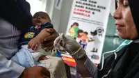 Petugas menyuntikan Vaksin Campak dan Rubella (MR) kepada bayi saat dilakukan imunisasi di sebuah puskesmas, Banda Aceh, Rabu (19/9). Pemerintah Aceh memperbolehkan penggunaan vaksin MR dengan alasan dalam kondisi darurat. (CHAIDEER MAHYUDDIN / AFP)