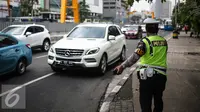 Petugas Polantas mengantur lalu lintas di kawasan Thamrin, Jakarta, Rabu (25/7). Kebijakan pembatasan kendaraan dengan penerapan pelat ganjil genap dimulai pada 27 Juli mendatang. (Liputan6.com/Faizal Fanani)