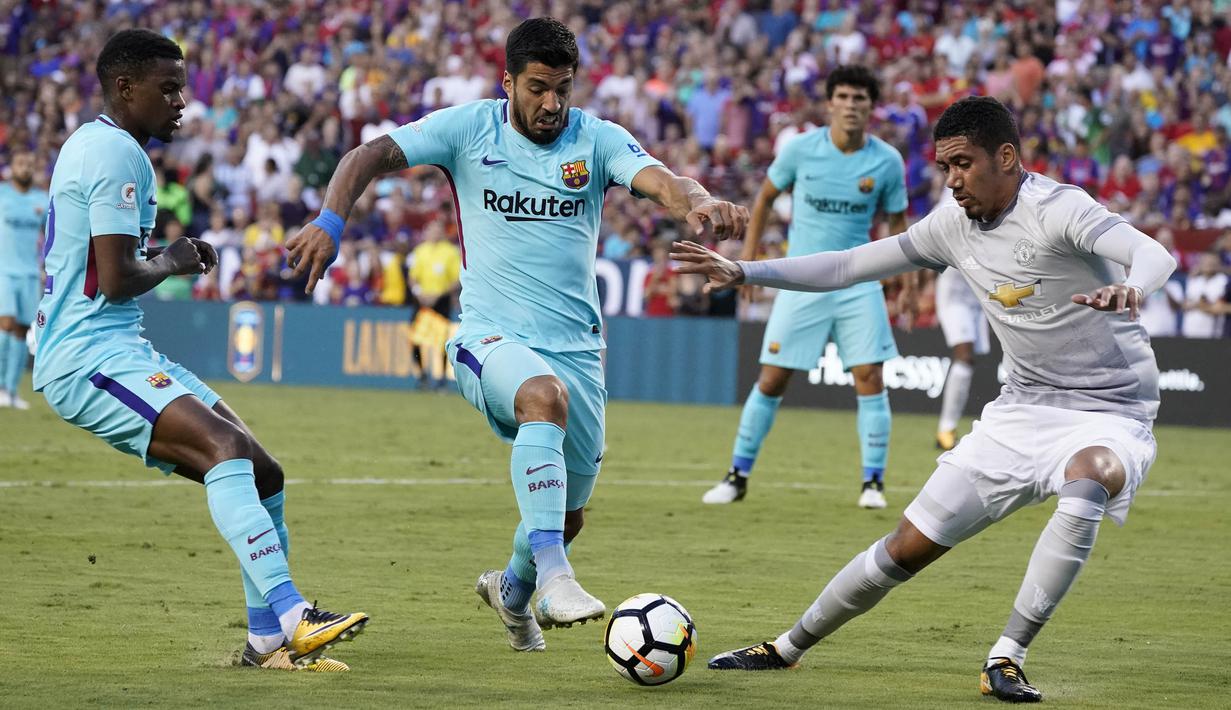 Striker Barcelona, Luis Suarez, berusaha melewati bek Manchester United, Chris Smailing, pada laga ICC di Stadion FedEx Field, Maryland, Rabu (26/7/2017). Barcelona menang 1-0 atas Manchester United. (EPA/Shawn Thew)