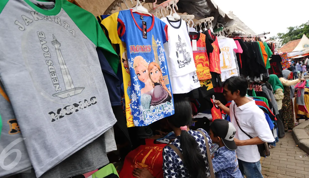Beberapa warga berburu kaos souvenir di kawasan Monumen Nasional, Jakarta, Minggu (25/12). Libur perayaan Natal 2016 dimanfaatkan sejumlah warga untuk berwisata di kawasan Monumen Nasional. (Liputan6.com/Helmi Fithriansyah)