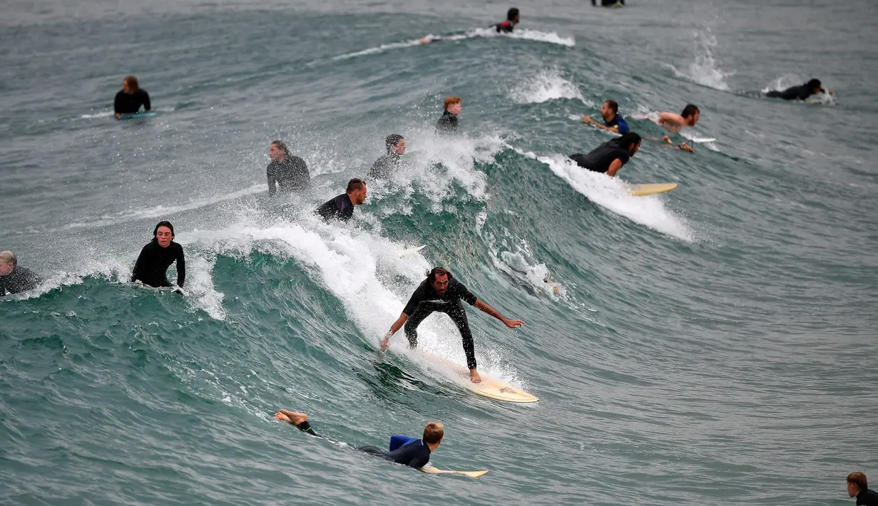 Orang-orang berselancar di Pantai Maroubra, Sydney (20/4/2020). Pihak berwenang di Sydney membuka kembali tiga pantai untuk aktivitas warga yang ingin berenang ataupun berselancar di tengah pembatasan sosial yang diberlakukan di tengah wabah corona (Covid-19). (AFP/Saeed Khan)