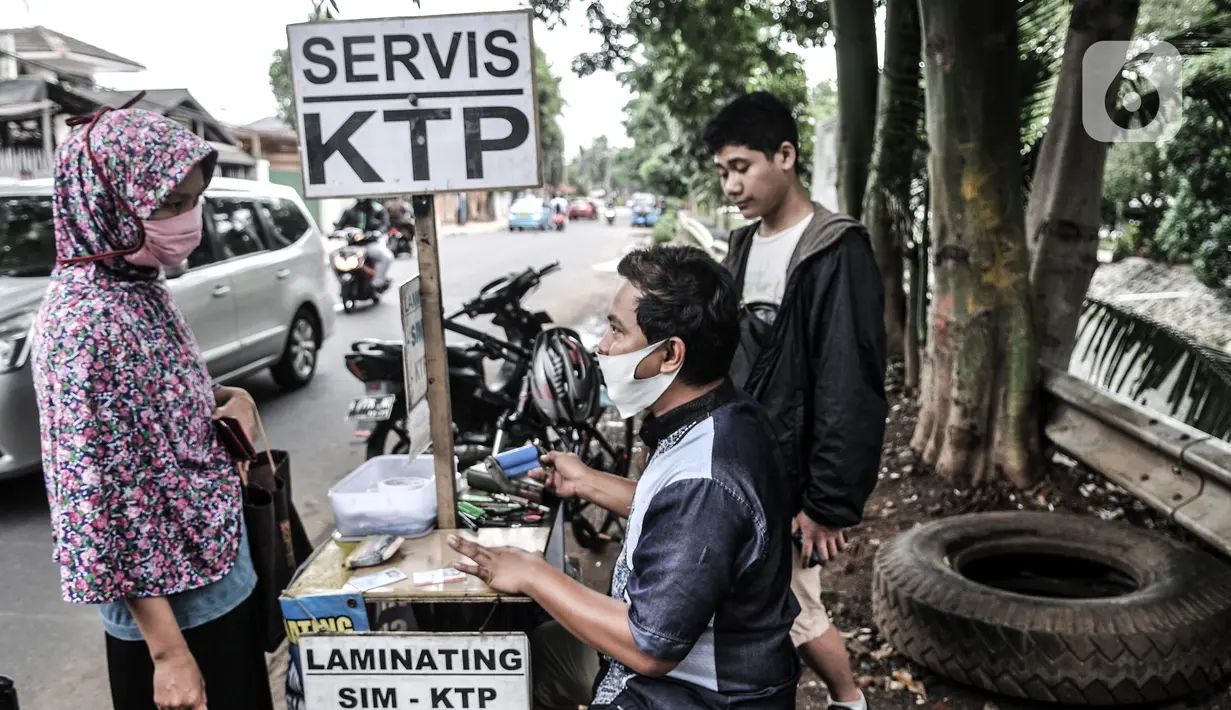 Feri (28) melayani pelanggan saat menyelesaikan jasa servis kartu tanda penduduk (KTP) di Jakarta, Kamis (21/1/2021). Feri mulai membuka jasanya sejak pukul 08.00 WIB hingga 17.00 WIB di pinggir jalan dengan lokasi yang tidak menetap alias berkeliling. (merdeka.com/Iqbal S. Nugroho)