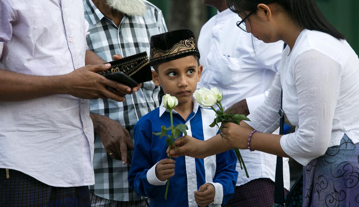 Umat Buddha Myanmar membagikan mawar putih kepada bocah Muslim setelah melaksanakan salat Id pada perayaaan Idul Fitri di kota Than Lyin, Yangon, Rabu (5/6/2019). Tindakan itu dilakukan beberapa minggu setelah kelompok garis keras berusaha menghapuskan doa selama bulan Ramadhan. (Sai Aung MAIN/AFP)