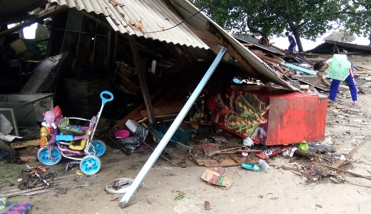 Seorang pria mencari barang-barang dari rumahnya yang rusak setelah tsunami menerjang Pantai Carita, di perairan Banten, Minggu (23/12). Data sementara jumlah korban dari bencana tsunami di Selat Sunda tercatat 43 orang meninggal dunia. (SEMI / AFP)