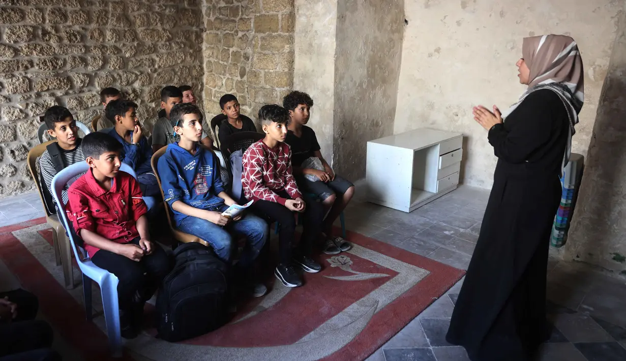 Anak-anak Palestina menghadiri kelas di sekolah bersejarah "Al-Kamaliya al-Othmanya" di Kota Tua Gaza yang menjadi bagian dari inisiatif sukarelawan yang diorganisir oleh para guru pengungsi, di Kota Gaza pada 2 November 2025. Diketahui, ada lebih dari 650 ribu anak kehilangan akses pendidikan formal sejak perang antara Israel dan Hamas memanas pada Oktober 2023. (Omar AL-QATTAA/AFP)
