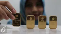 Petugas menunjukan emas batangan di kantor BNI Syariah, Jakarta, Senin (30/11). Harga jual-beli kembali (buyback) emas Antam turun Rp 1.000 usai akhir pekan kemarin naik di tengah turunnya harga emas global. (Liputan6.com/Angga Yuniar)
