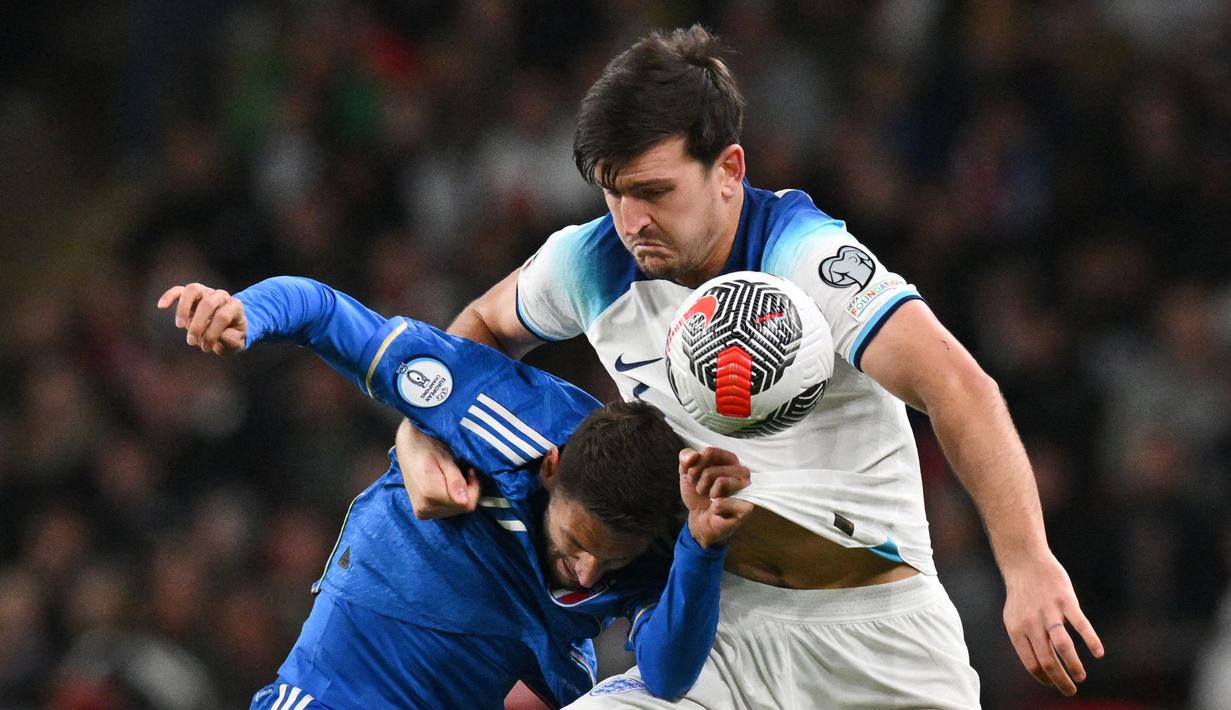 Pemain Timnas Inggris, Harry Maguire (kanan), berebut bola dengan pemain Timnas Italia, Domenico Berardi dalam laga lanjutan Kualifikasi Euro 2024 yang digelar di Wembley, London pada Rabu (18/10/2023) dini hari WIB. (AFP/Glyn Kirk)