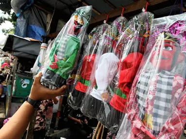 Pedagang menata miniatur ondel-ondel dagangannya di kawasan Kramat Pulo, Jakarta, Rabu (18/6/14). (Liputan6.com/Faizal Fanani)