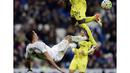 Cristiano Ronaldo melakukan tendangan salto saat dihadang pemain Villarreal, Eric Bally, pada lanjutan La Liga Spanyol di Stadion Santiago Bernabeu, Madrid, Rabu (20/4/2016) atau Kamis dini hari WIB. (AFP/Javier Soriano)