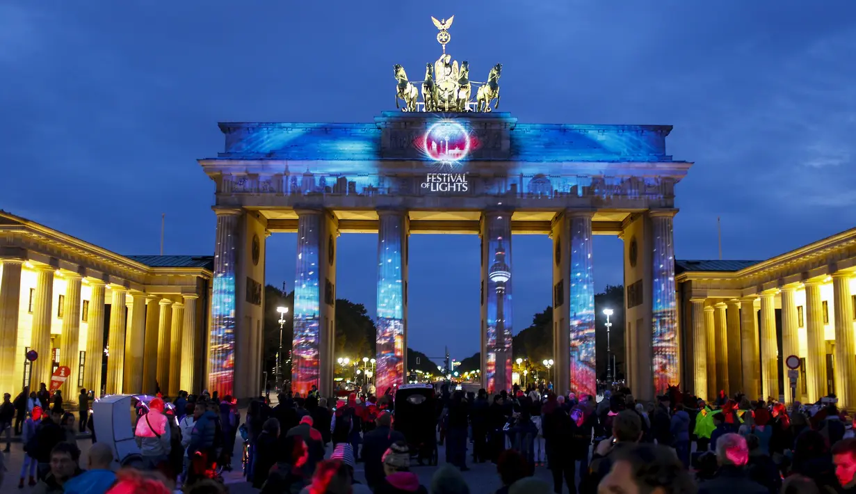 Wisatawan mengamati Gerbang Brandenburg yang dihiasi cahaya saat pembukaan Festival cahaya, Jerman, Sabtu (10/10/2015). Festival ini merupakan event tahunan yang diadakan setiap bulan Oktober selama dua belas hari.(REUTERS/Hannibal Hanschke)