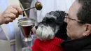 Seekor anjing peliharaan diberkati oleh pastor pada peringatan Hari santo Antonius di Madrid, Rabu (17/1). Pemberkatan hewan ini sebagai bentuk peringatan akan sosok San Anthony yang dikenal sebagai santo pelindung binatang. (PIERRE-PHILIPPE MARCOU/AFP)