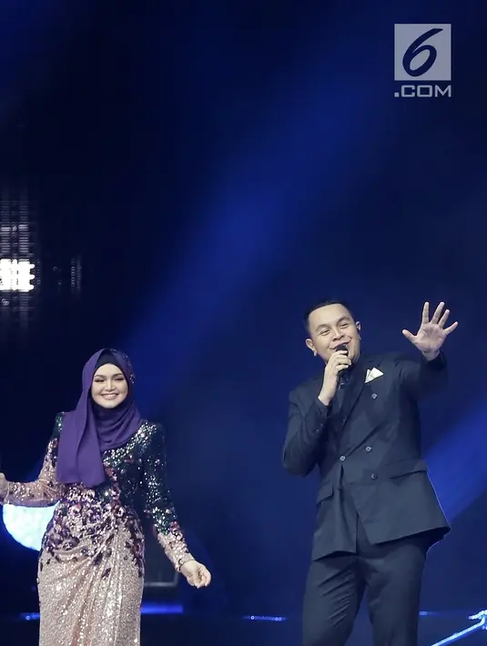 Penyanyi Siti Nurhaliza (kiri) duet dengan Tulus dalam konser 'Dato Sri Siti Nurhaliza on Tour' di Istora Senayan, Jakarta, Kamis (21/2). Duet Siti dengan Tulus sontak membuat para penonton bernyanyi dan merekam momen tersebut. (Fimela.com/Bambang E Ros)