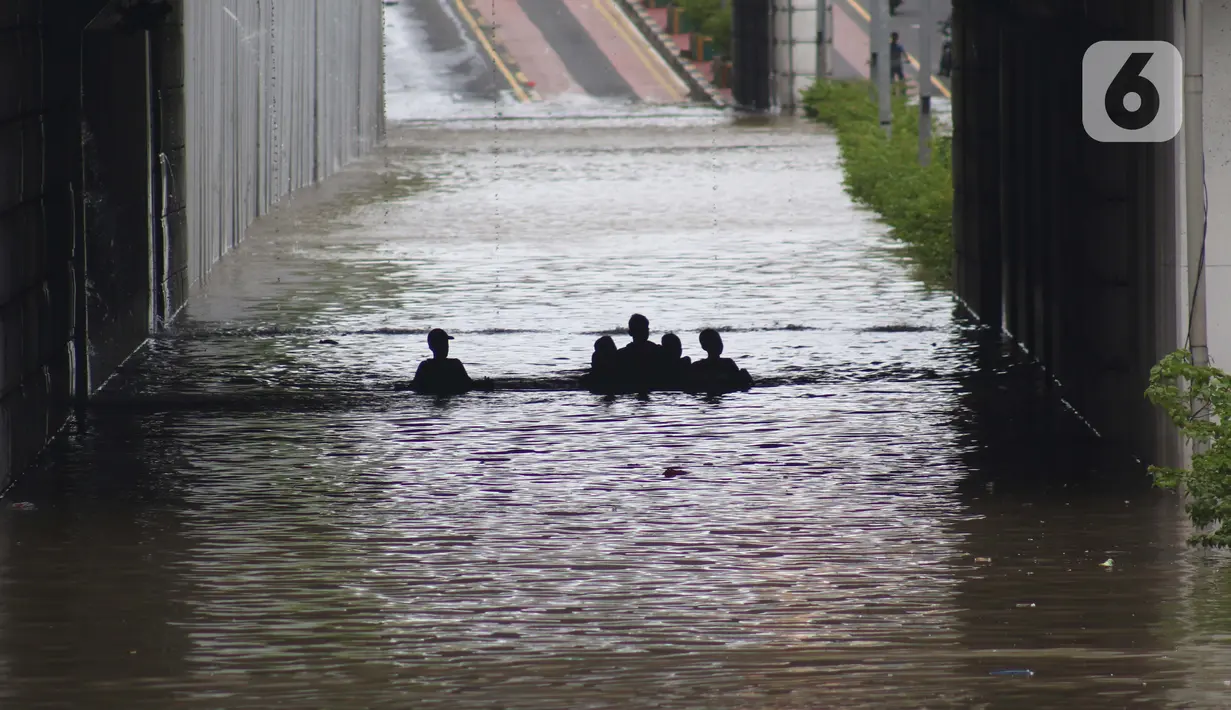Warga melintasi banjir di terowongan Jalan Angkasa, Jakarta, Selasa (25/2/2020). Hujan yang mengguyur Jakarta sejak Senin (24/2) malam membuat sejumlah kali meluap dan menyebabkan banjir di terowongan tersebut. (Liputan6.com/Helmi Fithriansyah)