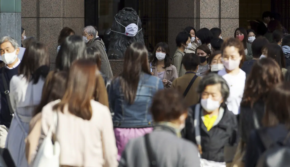 Orang-orang yang mengenakan masker pelindung untuk membantu mengekang penyebaran virus corona COVID-19 berjalan di sepanjang penyeberangan pejalan kaki di Tokyo, Jepang, Kamis (15/4/2021). Tokyo mengonfirmasi lebih dari 700 kasus baru COVID-19 pada 15 April 2021. (AP Photo/Eugene Hoshiko)