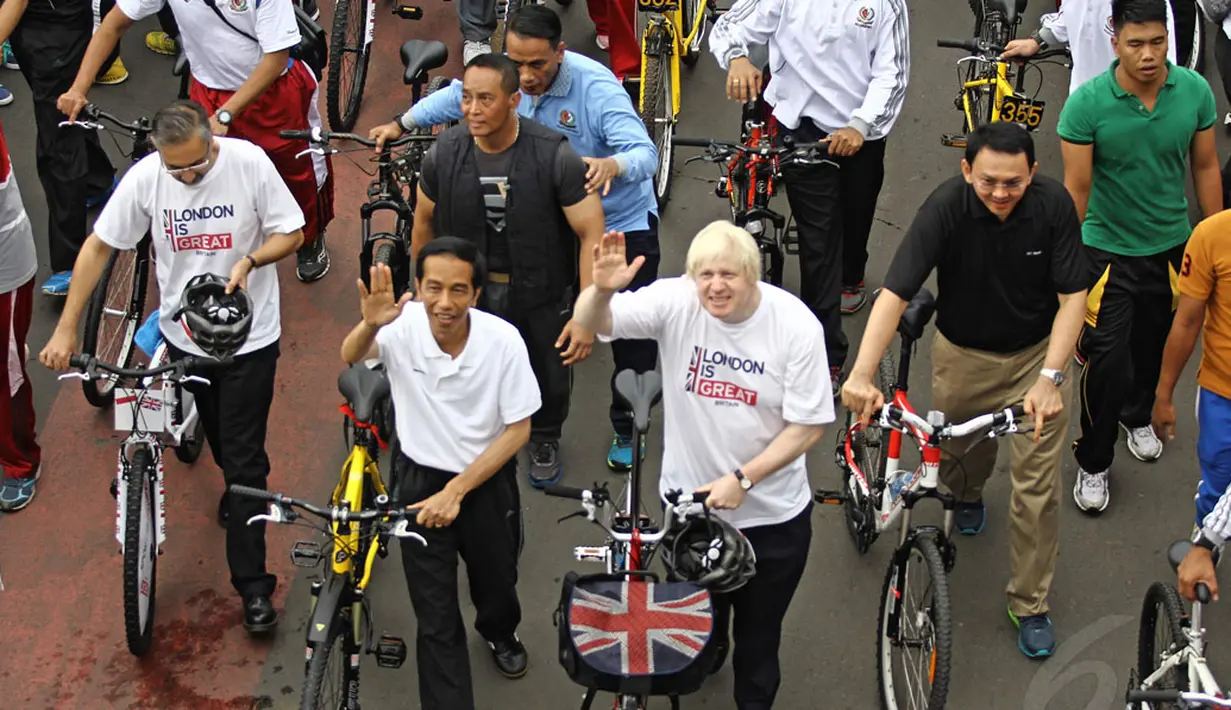 Presiden Joko Widodo bersama Walikota London, Boris Johnson melambaikan tangan saat bersepeda bersama di kawasan Bundaran HI Jakarta, Minggu (30/11/2014). (Liputan6.com/Faizal Fanani)