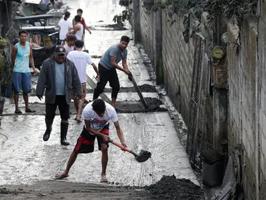 Warga membersihkan jalanan dari abu vulkanik setelah erupsi Gunung Taal di Tagaytay, Provinsi Cavite, Filipina, Senin (13/1/2020). Gunung yang terakhir meletus pada tahun 1977 tersebut melontarkan abu vulkanik mencapai 50.000 kaki (15.000 meter) ke atmosfer. (AP Photo/Bullit Marquez)
