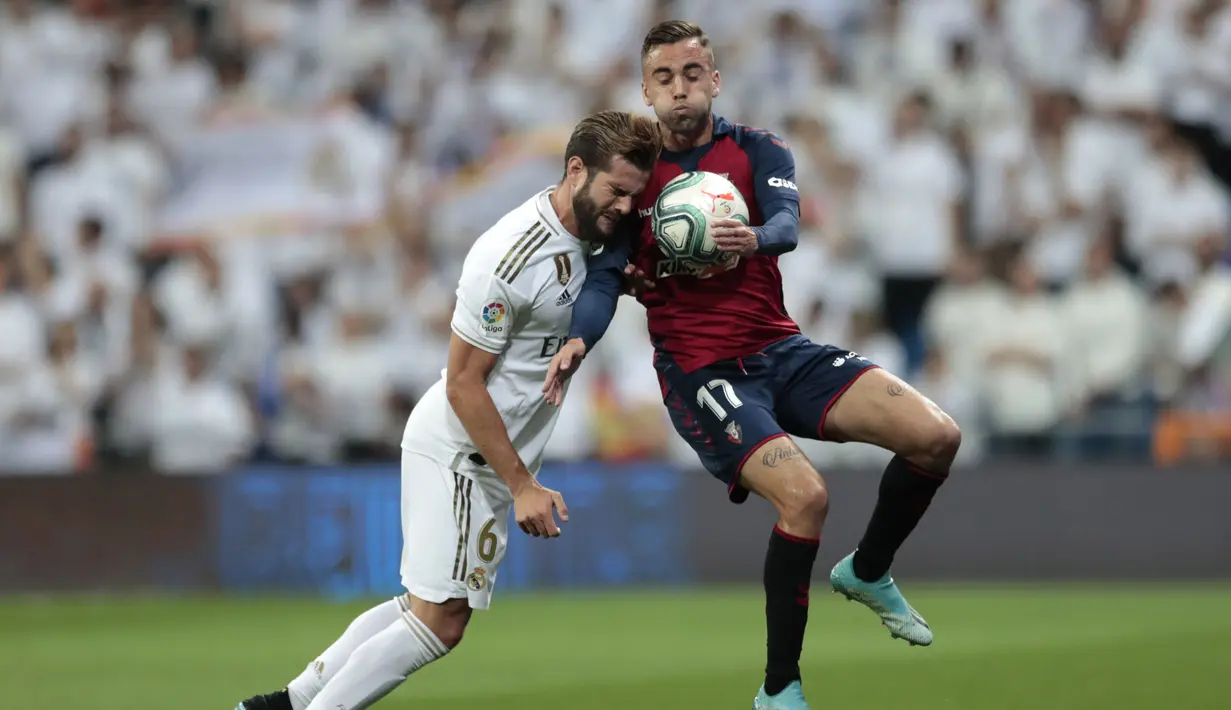 Bek Real Madrid, Nacho berebut bola dengan pemain Osasuna, Robert Ibanez pada lanjutan pertandingan La Liga di stadion Santiago Bernabeu, Spanyol (25/9/2019). Dengan kemenangan ini Real Madrid ke Puncak Klasemen La Liga dengan poin 14. (AP Photo/Bernat Armangue)