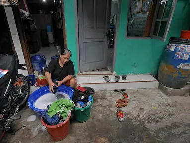 Warga mencuci pakaian di depan rumahnya di Kawasan Muara Baru, Jakarta, Selasa (9/7/2019). Pada saat musim kemarau air sumur tidak mengalir deras, untuk memenuhi air bersih warga dalam sehari mengeluarkan uang Rp. 15.000 untuk membeli enam derigen untuk air bersih. (Liputan6.com/Herman Zakharia)