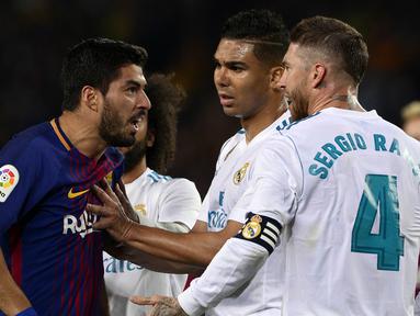 Striker Barcelona, Luis Suarez, bersitegang dengan bek Real Madrid, Sergio Ramos, pada laga La Liga Spanyol di Stadion Camp Nou, Barcelona, Minggu (6/5/2018). Kedua klub bermain imbang 2-2. (AFP/Josep Lago)