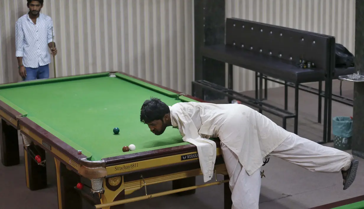 Mohammad Ikram bermain snooker dengan dagunya di sebuah klub snooker lokal di kota Samundri, Pakistan, Minggu (25/10/2020). Dia tinggal di kota pedesaan terpencil di provinsi Punjab dan kecacatan fisiknya tidak menghalangi impian masa kecilnya untuk bermain snooker. (AP Photo/Anjum Naveed)