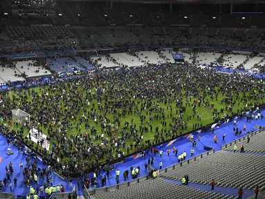 Ribuan Penonton berhamburan di lapangan stadion Stade de France saat menyaksikan pertandingan persahabatan antara Prancis melawan Jerman di Saint-Denis, Paris, (13/11). Serangan bom terjadi di dekat stadion Stade de France Prancis. (AFP PHOTO/FRANCK FIFE)