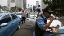 Seorang sopir taksi saat makan siang selama aksi protes terhadap aplikasi transportasi di Jakarta, Selasa (22/3). Ribuan Sopir taksi turun ke jalan. Mereka berdemonstrasi menolak keberadaan angkutan online berpelat hitam. (REUTERS/Beawiharta)