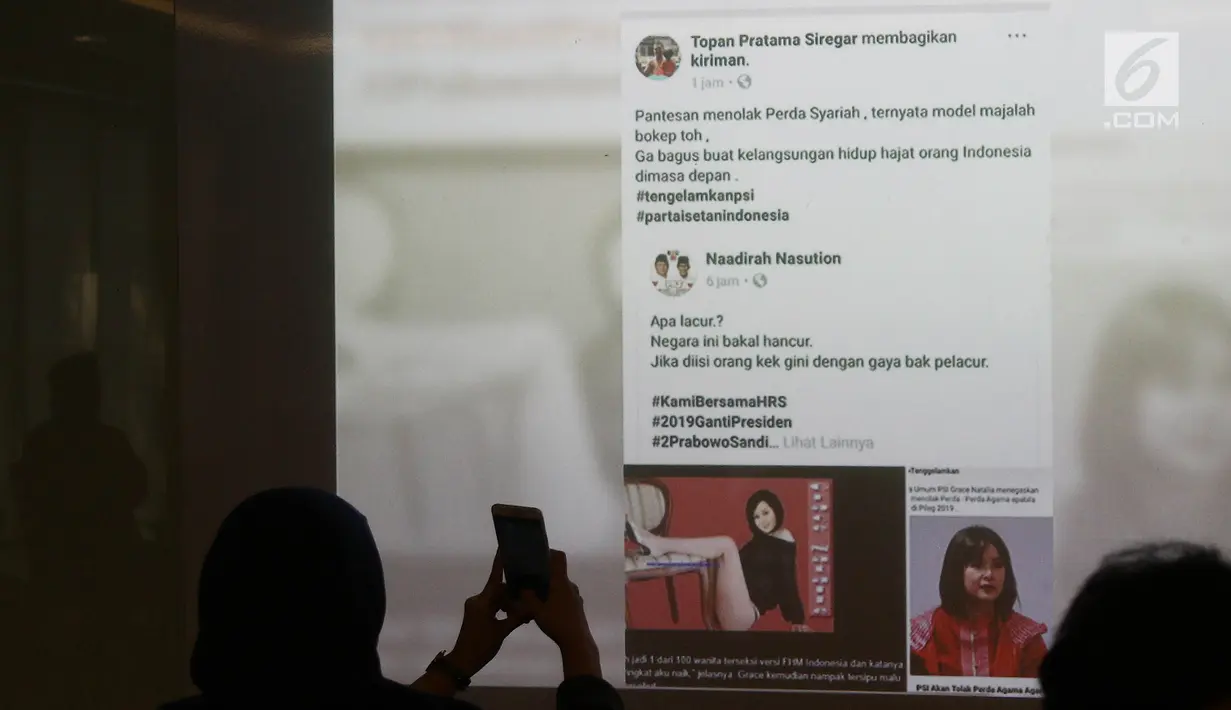 Seseorang mengambil gambar postingan fitnah dan foto hoax terhadap Ketua Umum Partai Solidaritas Indonesia (PSI) Grace Natalie, Taufan Pratama saat jumpa pers permintaan maaf di Jakarta, Senin (19/11). (Liputan6.com/Herman Zakharia)