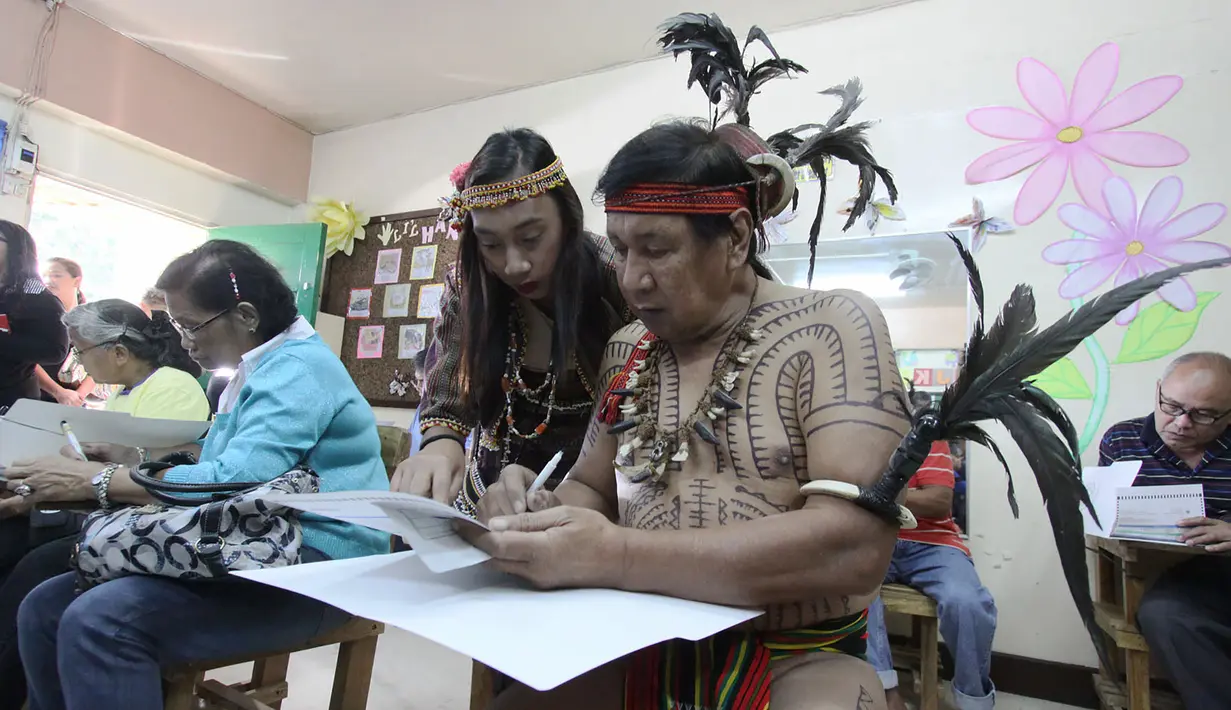 Kepala suku Igorot, Nicolas Cawed dibantu putrinya Mia Nicole mengisi kertas suara dalam pemilihan presiden di sebuah TPS di Baguio City, Manila Utara, Senin (9/5). Sekitar 50 juta warga Filipina mengikuti pemilihan Presiden. (AFP PHOTO/JJ LANDINGIN)