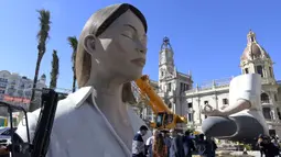 Patung raksasa yang akan ditampilkan di festival Las Fallas atau festival api terlihat sebelum dipasangkan masker di Valencia, Spanyol, Rabu (11/3/2020). Festival Fallas yang akan berlangsung pada 13 Maret telah dibatalkan karena wabah coronavirus. (AFP/Jose Jordan)