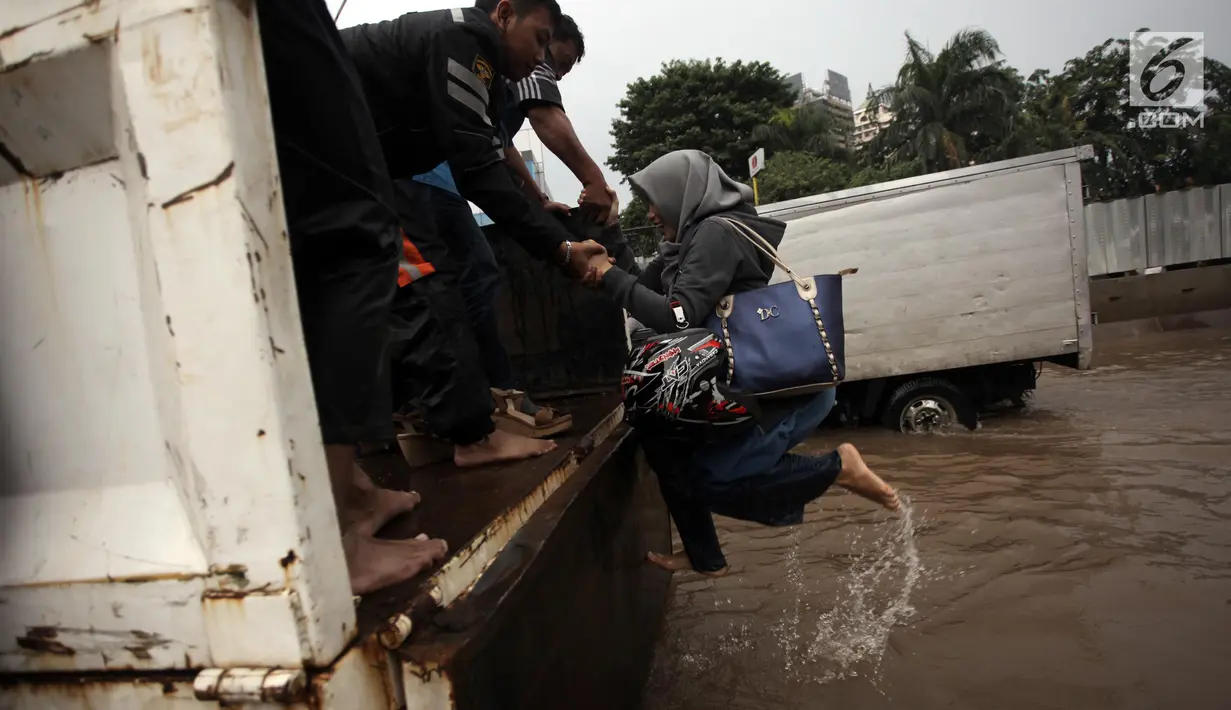 Warga berusaha naik ke truk terbuka ketika banjir merendam di Jalan Boulevard Raya, Kelapa Gading, Jakarta, Kamis (15/2). Hujan yang mengguyur Jakarta mengakibatkan kawasan Kelapa Gading terendam banjir. (Liputan6.com/Arya Manggala)
